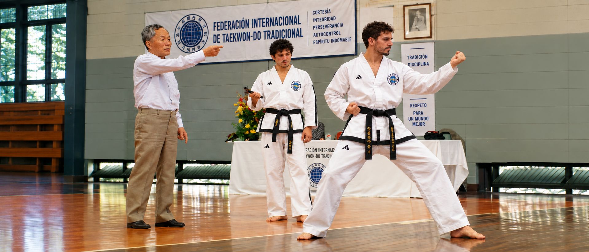 Maestro de Taekwon-Do corrigiendo a dos practicantes con dobok adidas
